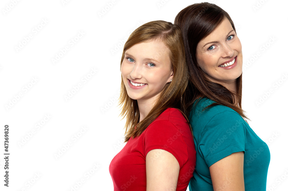 Joyous trendy mom and daughter standing back to back Joyous trendy mom and daughter standing back to back