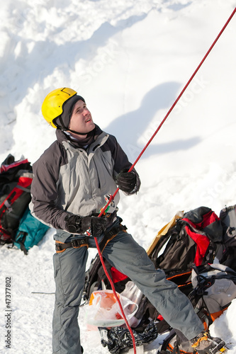 Man supports climber on frozen waterfall