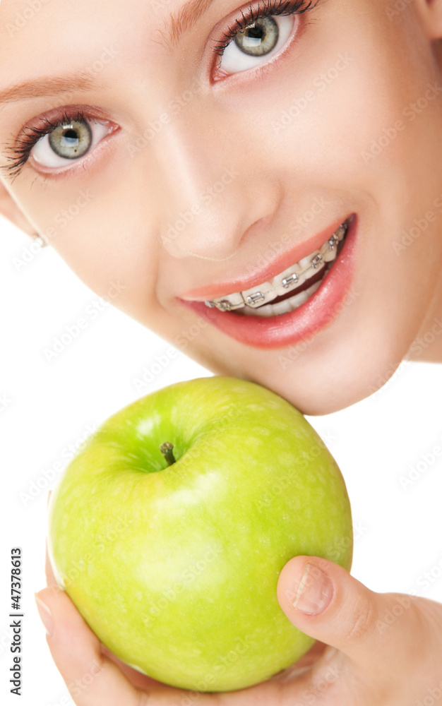 Cute girl in braces with green apple on white background