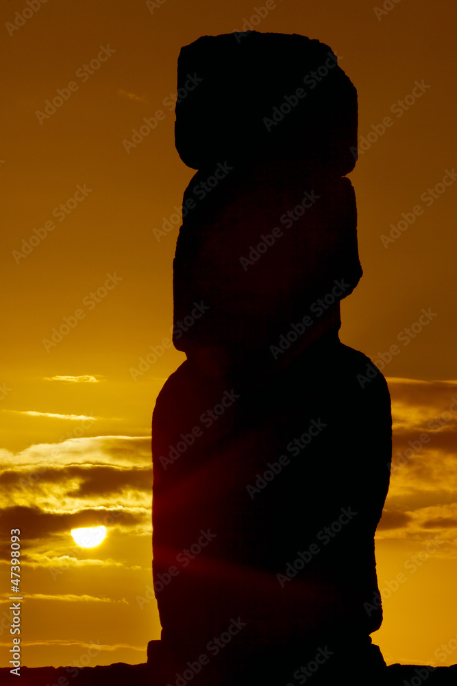 Silhouette of a moai against orange sunrise