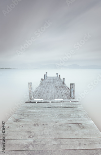 Wooden pier on lake in a cloudy and foggy mood.