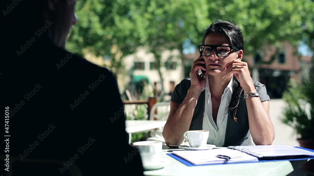 Businesspeople sitting at patio table outside with documents and Businesspeople sitting at patio table outside with documents and