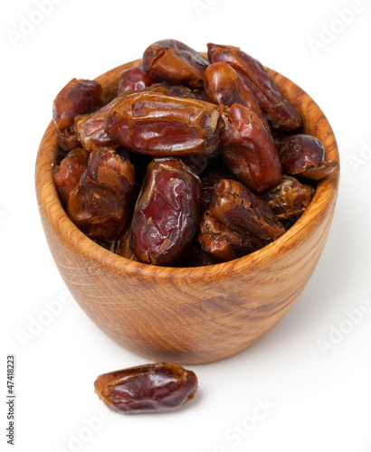 dried dates in wooden bowl isolated on white