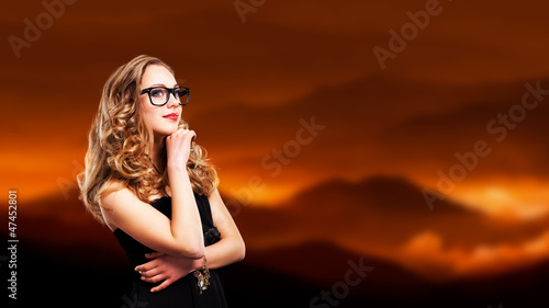 junge blonde Frau mit Nerdbrille vor Berglandschaft