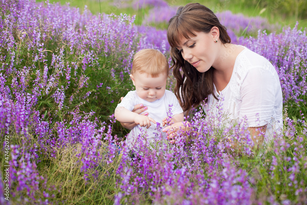 Mother with cute baby posing sitting on field of purple flowers Mother with cute baby posing sitting on field of purple flowers