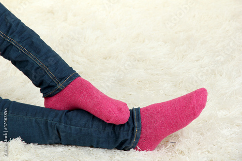 Female legs in colorful socks on  white carpet background