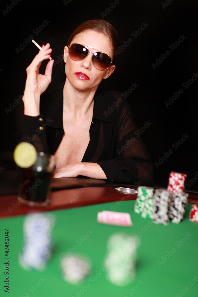 Frau mit Sonnenbrille und Zigarette am Pokertisch Frau mit Sonnenbrille und Zigarette am Pokertisch