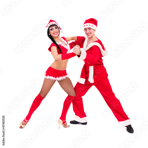 Happy young couple wearing santa claus clothes dancing