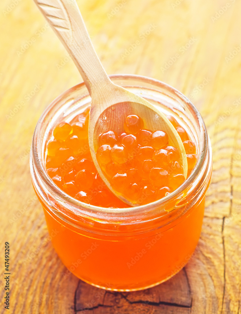Red salmon caviar in the wooden bowl and spoon Red salmon caviar in the wooden bowl and spoon