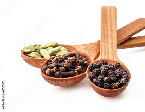 Spices on wooden spoons isolated on white background photo