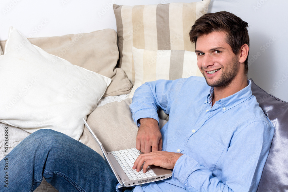 Young man using laptop on couch Young man using laptop on couch