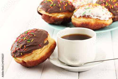 Tasty donuts on color plate on light wooden background
