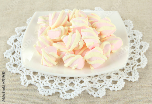 Marshmallows on plate on light background