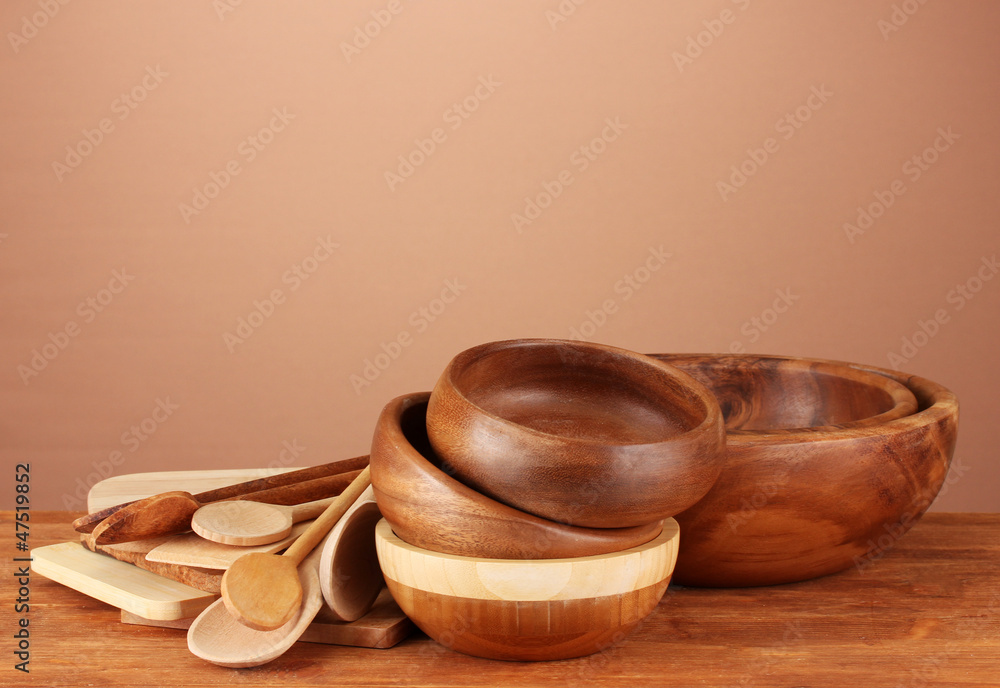 Wooden kitchen utensils on table on brown background Wooden kitchen utensils on table on brown background