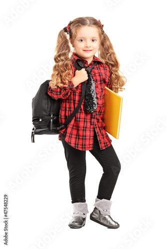 Llittle girl standing with backpack and book