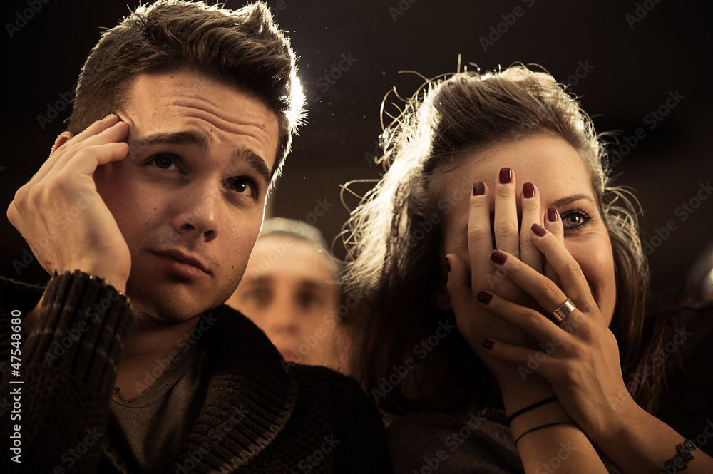 Naklejka premium Couple scared at the cinema, watching horror movie