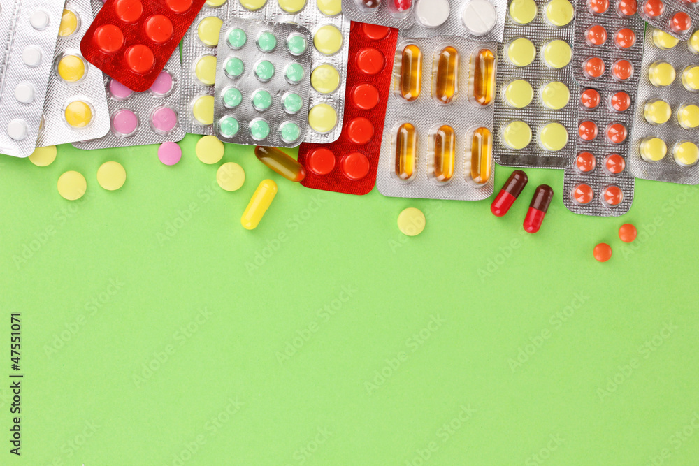 Capsules and pills packed in blisters on green background