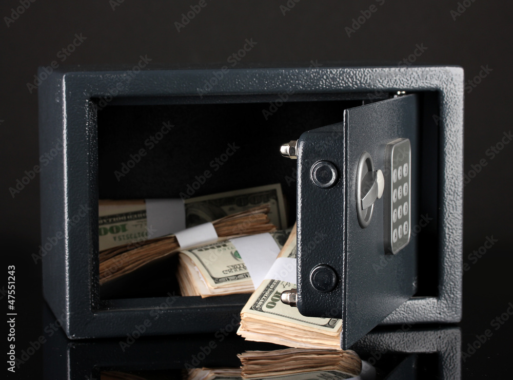 Naklejka premium Money in open safe isolated on black