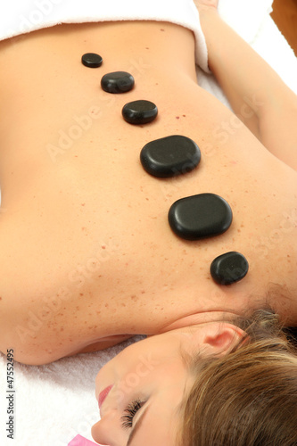 beautiful young woman in spa salon with spa stones, close up