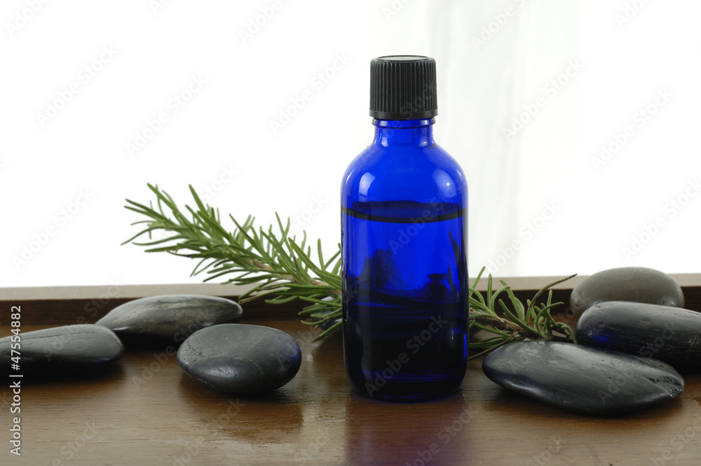 bottle of aromatherapy oil and fresh green leaves bottle of aromatherapy oil and fresh green leaves