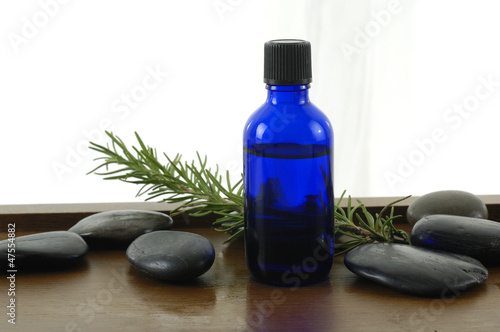 bottle of aromatherapy oil and fresh green leaves