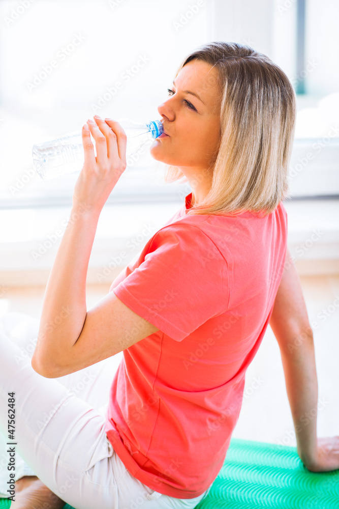 Pretty young woman refreshing during workout at home Pretty young woman refreshing during workout at home