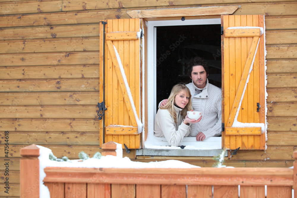 Couple looking out from chalet window Couple looking out from chalet window