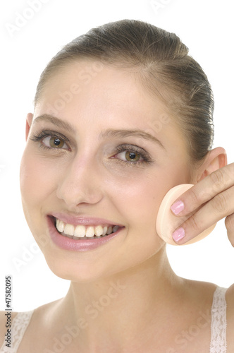 Close up young woman applying face foundation