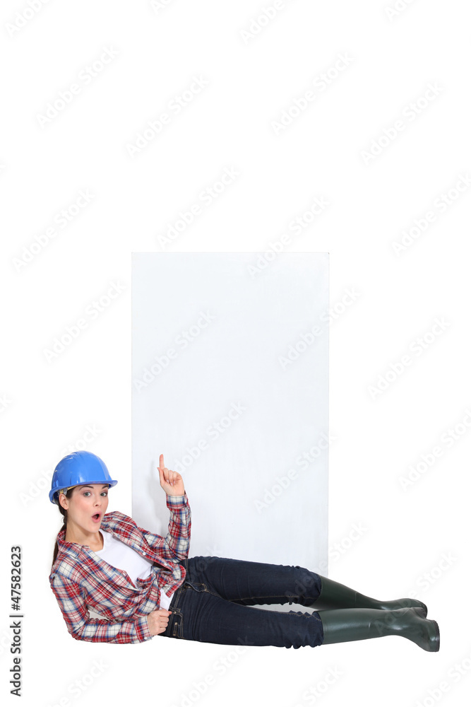 A lying female construction worker pointing at the sky. A lying female construction worker pointing at the sky.