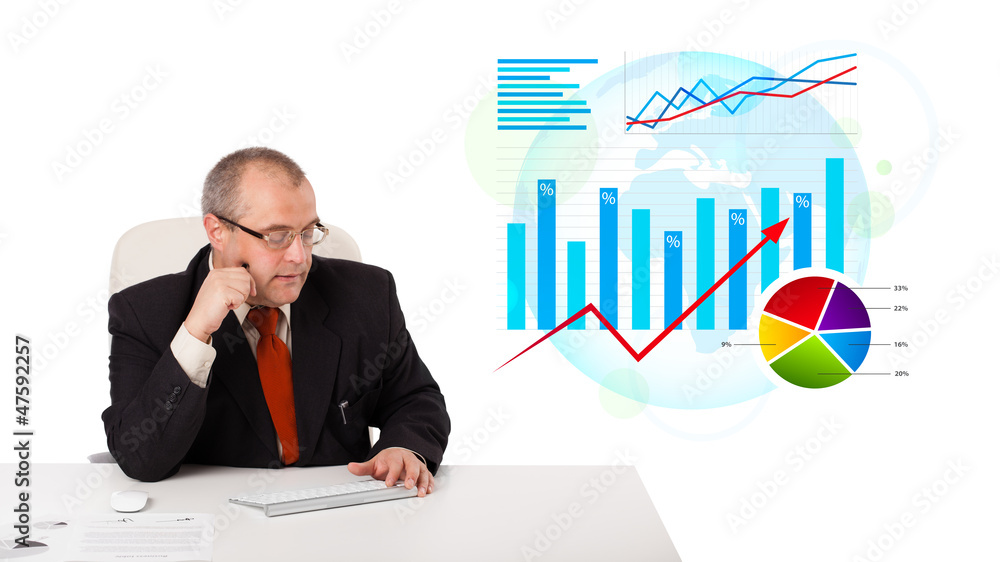 Businessman sitting at desk with statistics Businessman sitting at desk with statistics