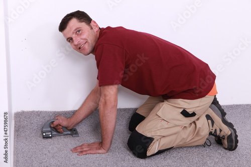 man on all fours stapling carpet
