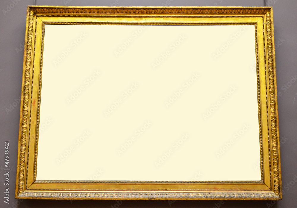 Fototapeta premium Empty golden picture frame hanging on wall