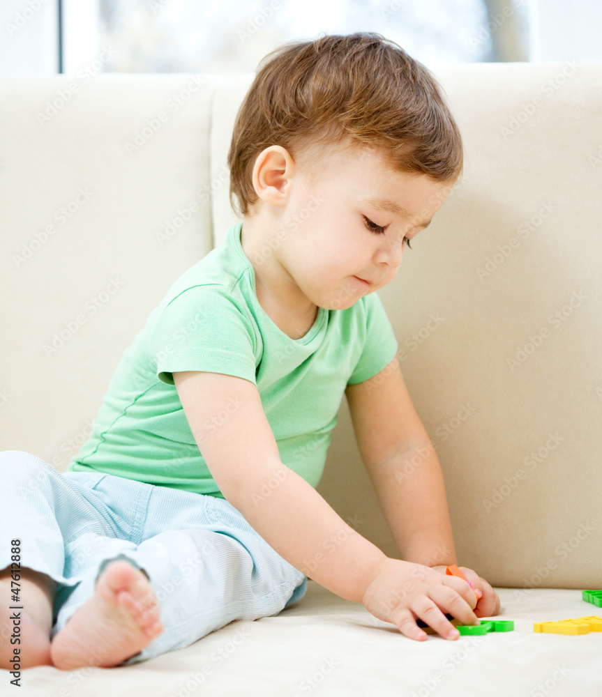 Boy is playing while sitting on couch Boy is playing while sitting on couch