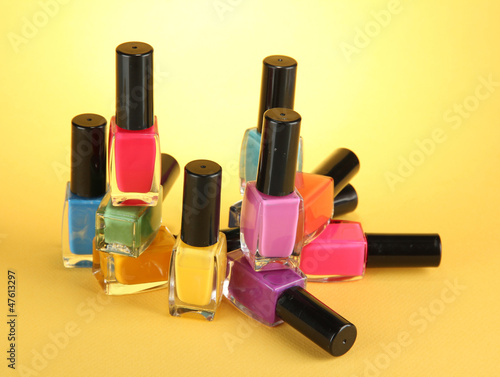 Group of bright nail polishes, on yellow background © Africa Studio