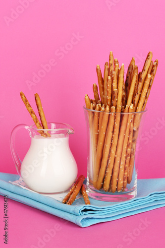 Tasty crispy sticks in glass cup on pink background