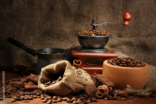 Coffee grinder, turk and cup of coffee on burlap background