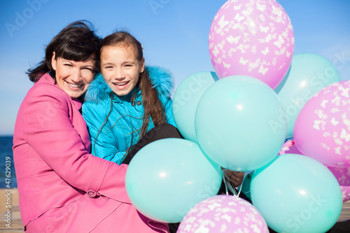 Mom and daughter posing on the beach in autumn with a balloons