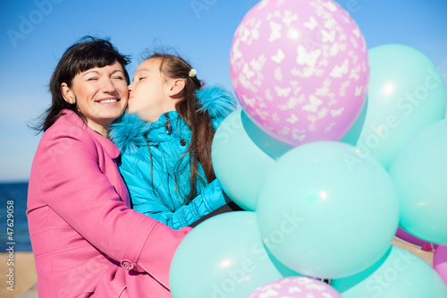 Mom and daughter posing on the beach in autumn with a balloons