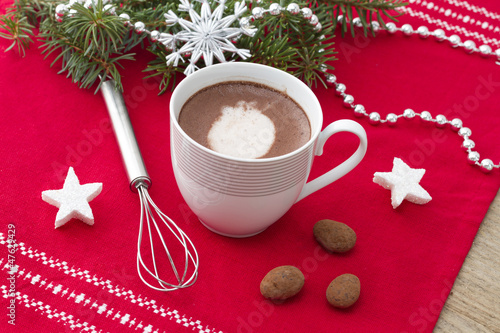 Cocoa cup with beater & chocolates on red traycloth photo