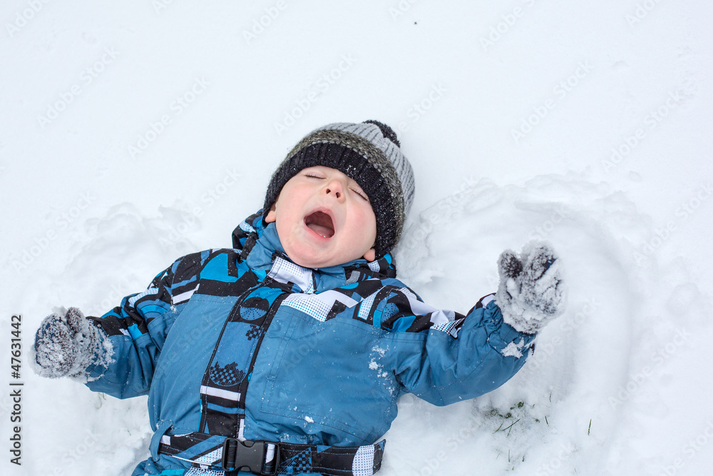 Adorable toddler boy making angel on snow Adorable toddler boy making angel on snow