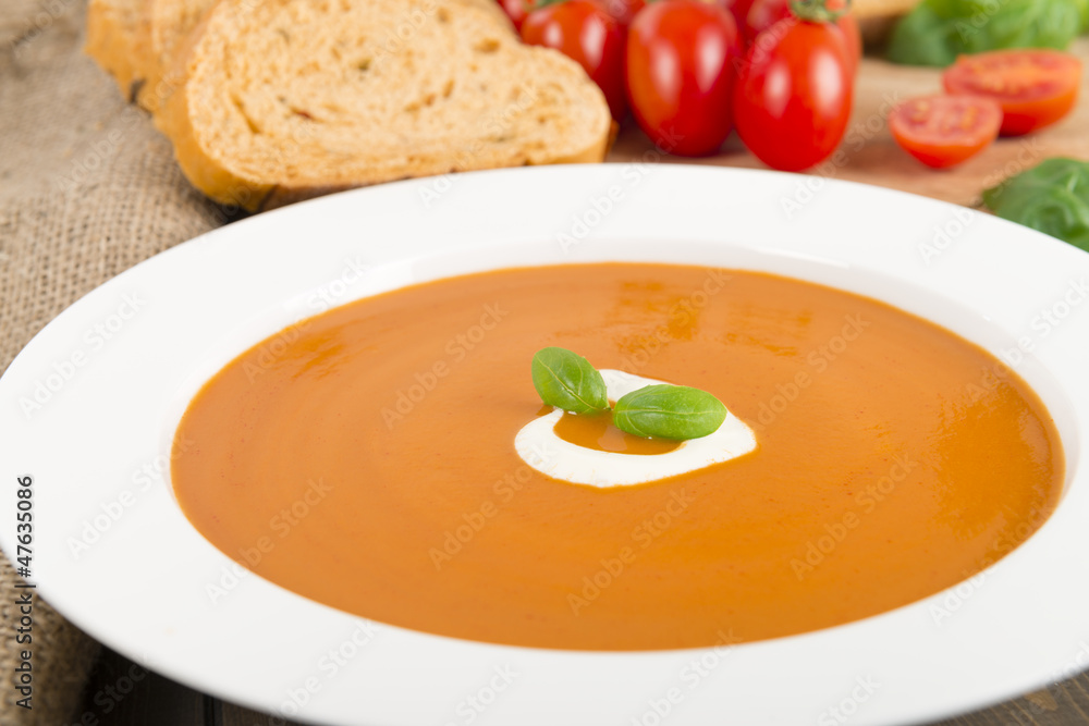 Cream of tomato soup with crème fraîche, bread & basil leaves