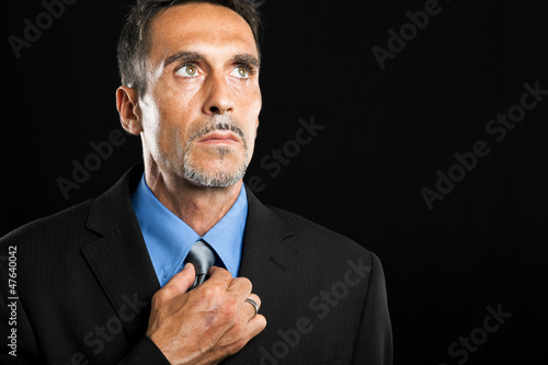 Businessman adjusting his look on a dark background