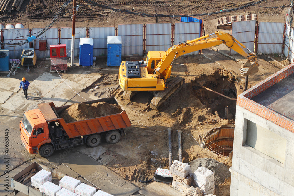 Fototapeta premium Excavator digs hole at construction site.