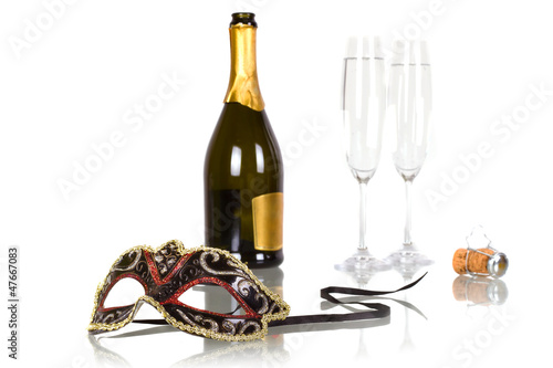Bottle of champagne with two flutes and party mask