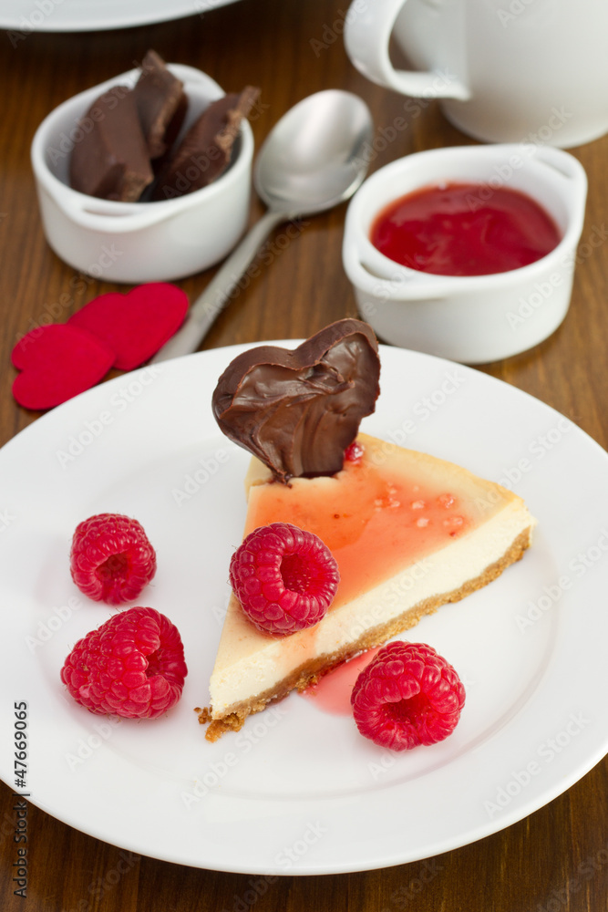 cheesecake with raspberries and chocolate heart on the plate cheesecake with raspberries and chocolate heart on the plate