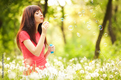 Happy woman blowing bubbles in the park