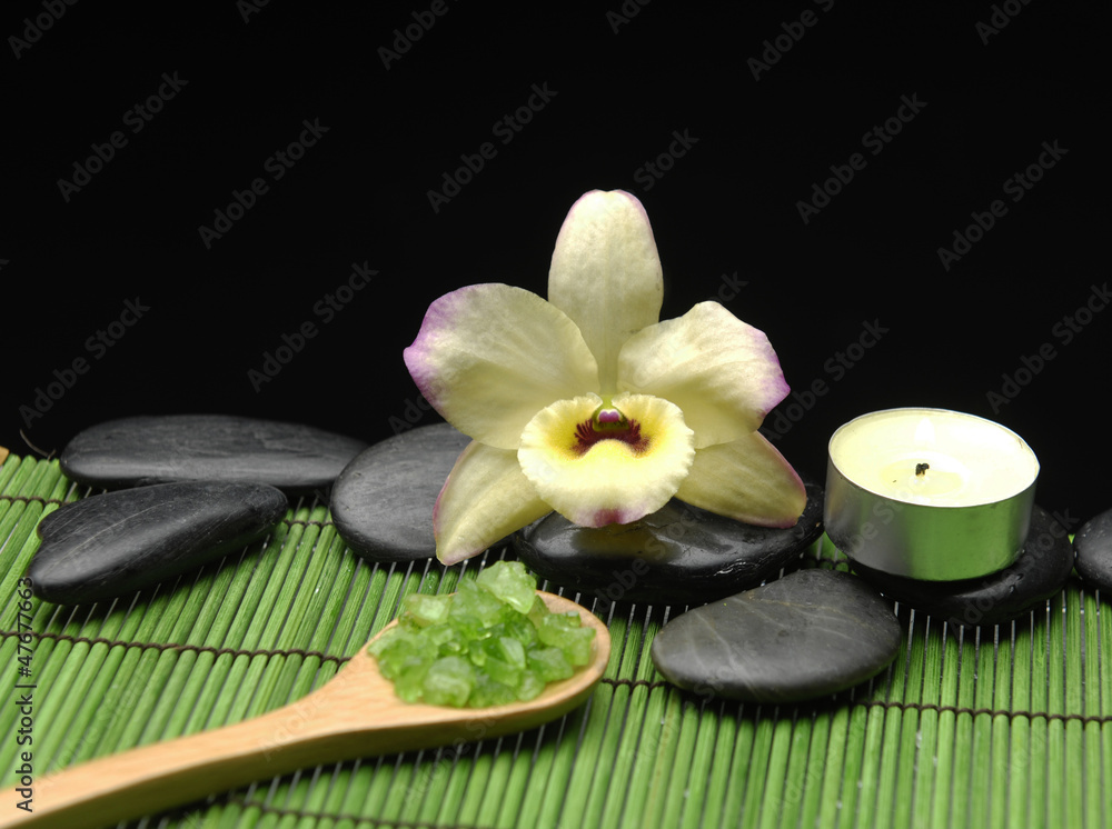 Green salt in spoon with yellow orchid with candle