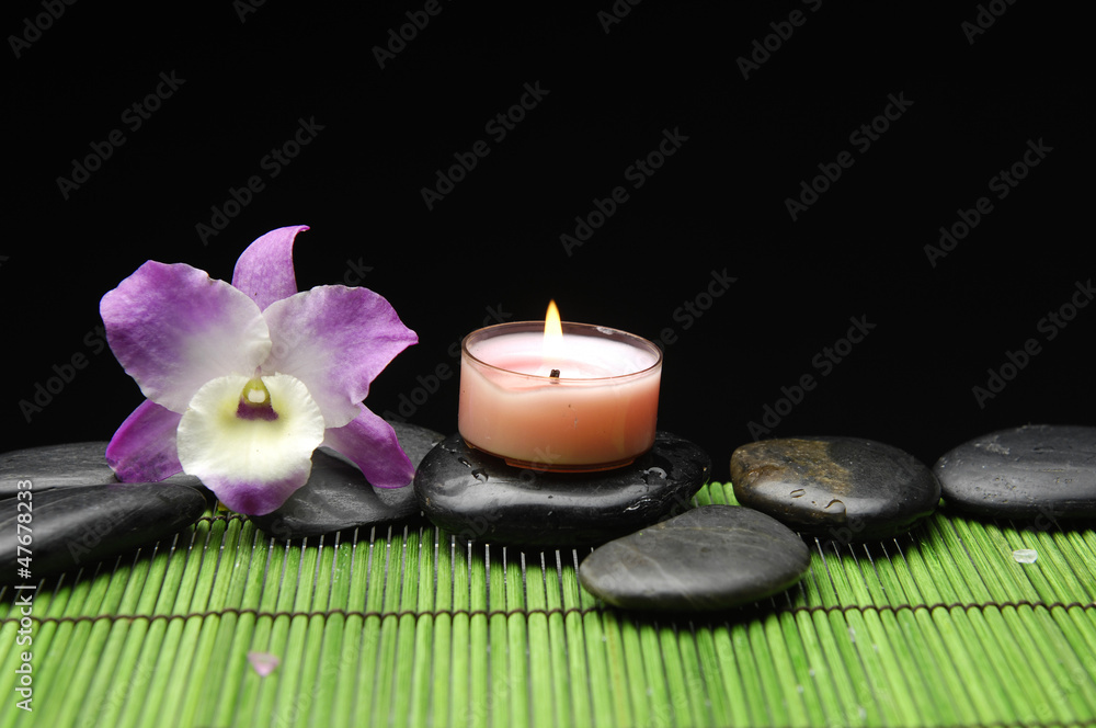 pink orchid with black stone and candle on green mat pink orchid with black stone and candle on green mat