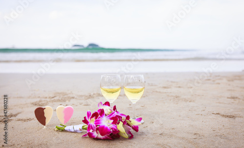 Романтический символ любви. Цветы и вино на песчаном пляже.