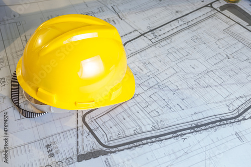 Construction plans with yellow helmet